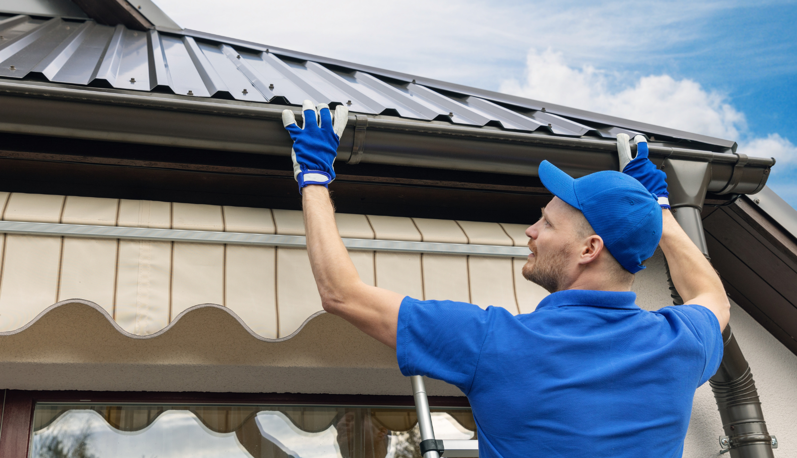 Man Installing Steel Gutter against the grey colorbond rooftop 